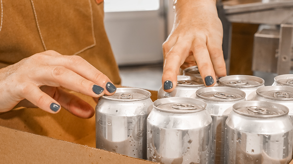 Brewer packing freshly canned kombucha into a case at Firefly Brew’s production facility.